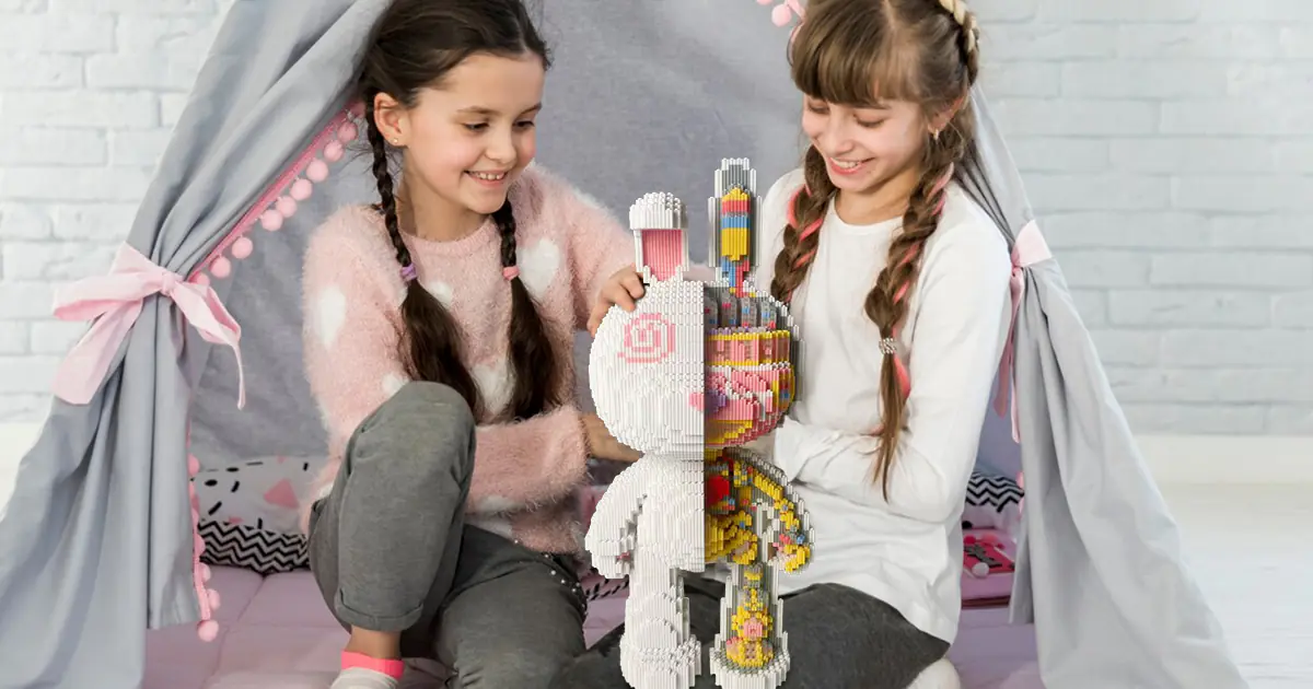 two girls sitting on a blanket holding a toy