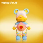 Constructed from 6,652 interlocking ​​building blocks​​, this ​​toy​​ showcases a gradient pink-to-yellow face, light blue ears with yellow centers, and a red heart emblem on its chest. Limbs feature alternating pink, yellow, and blue joints for dynamic contrast. The golden-yellow backdrop and "YAOYAO PLAY" branding highlight its child-friendly proportions and modular adaptability, ideal for hands-on builders.