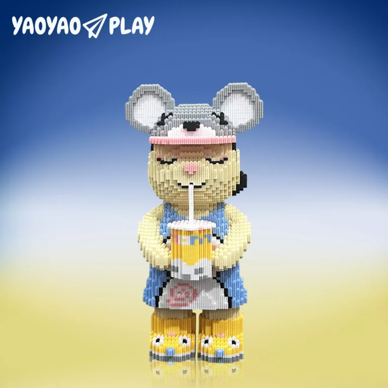 A ​​Brick Bear toy​​ holding a striped cup, labeled "YAOYAO PLAY," posed against a blue-to-yellow ombre backdrop.
